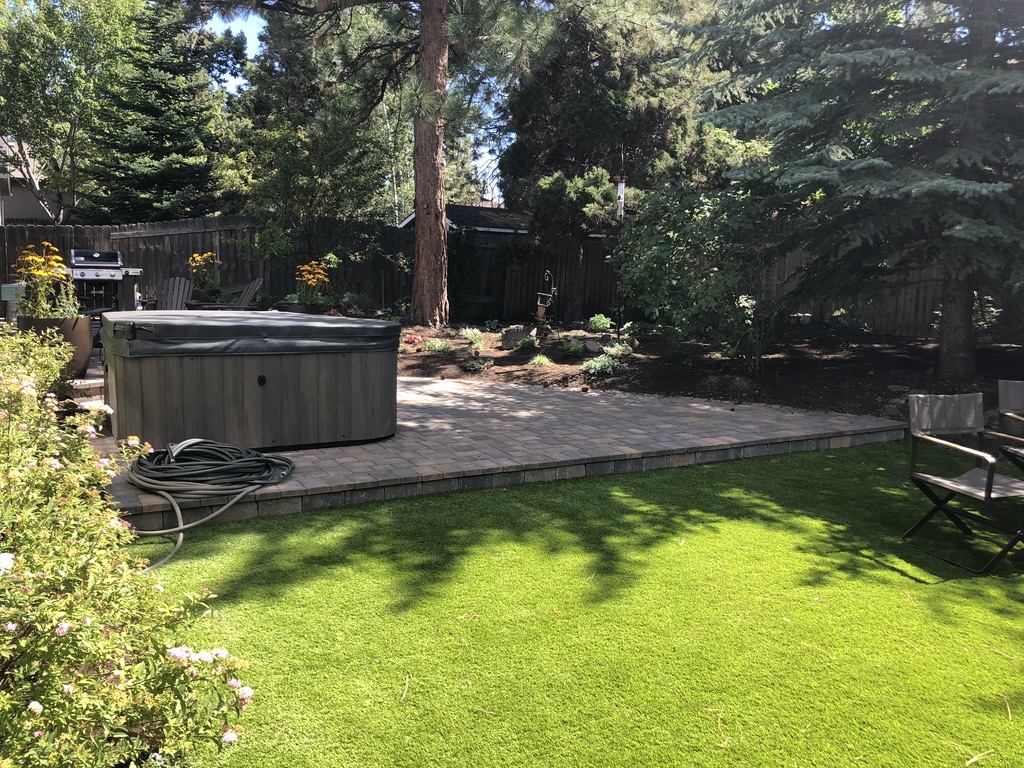 backyard with artificial synlawn turf with trees and a hot tub happy Bend Oregon lawn