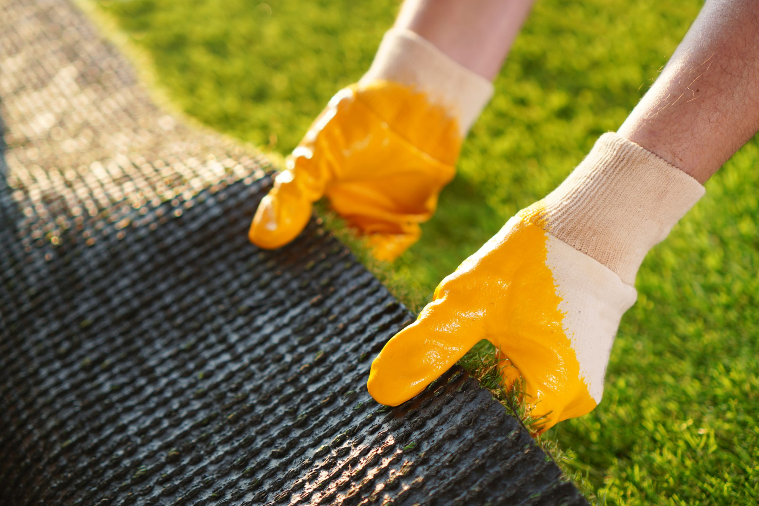 Artificial grass roll in worker hands Central Oregon summer artificial synlawn turf